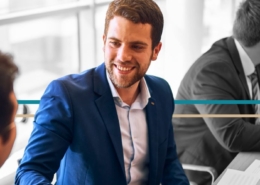 a businessman talks with another professional at a conference table