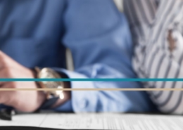 A man's and woman's hands seen resting on a table together with a pen and paperwork