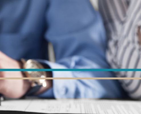 A man's and woman's hands seen resting on a table together with a pen and paperwork