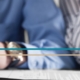 A man's and woman's hands seen resting on a table together with a pen and paperwork