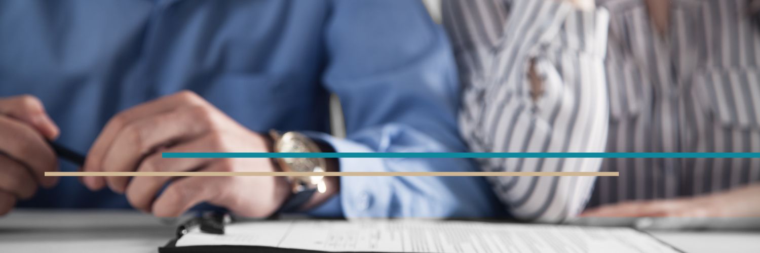 A man's and woman's hands seen resting on a table together with a pen and paperwork