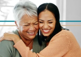 A young woman hugs an older woman while both are smiling
