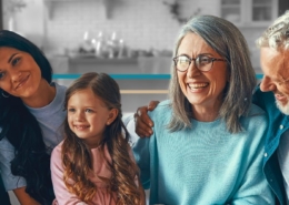 younger grandparents sitting on a couch with a young couple and their little girl