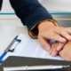 A woman in a suit jacket puts her hand over the hand of another person soothingly