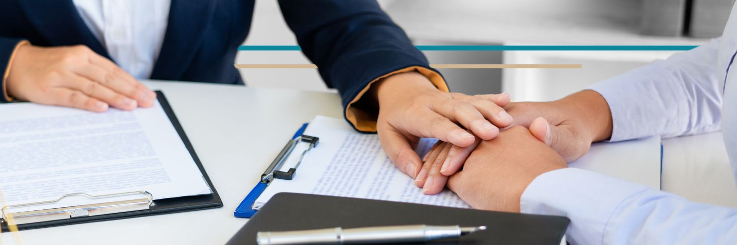 A woman in a suit jacket puts her hand over the hand of another person soothingly