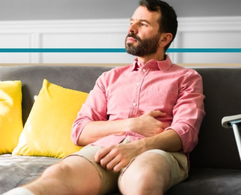 a man with a leg in a cast sitting on a couch looking out the window