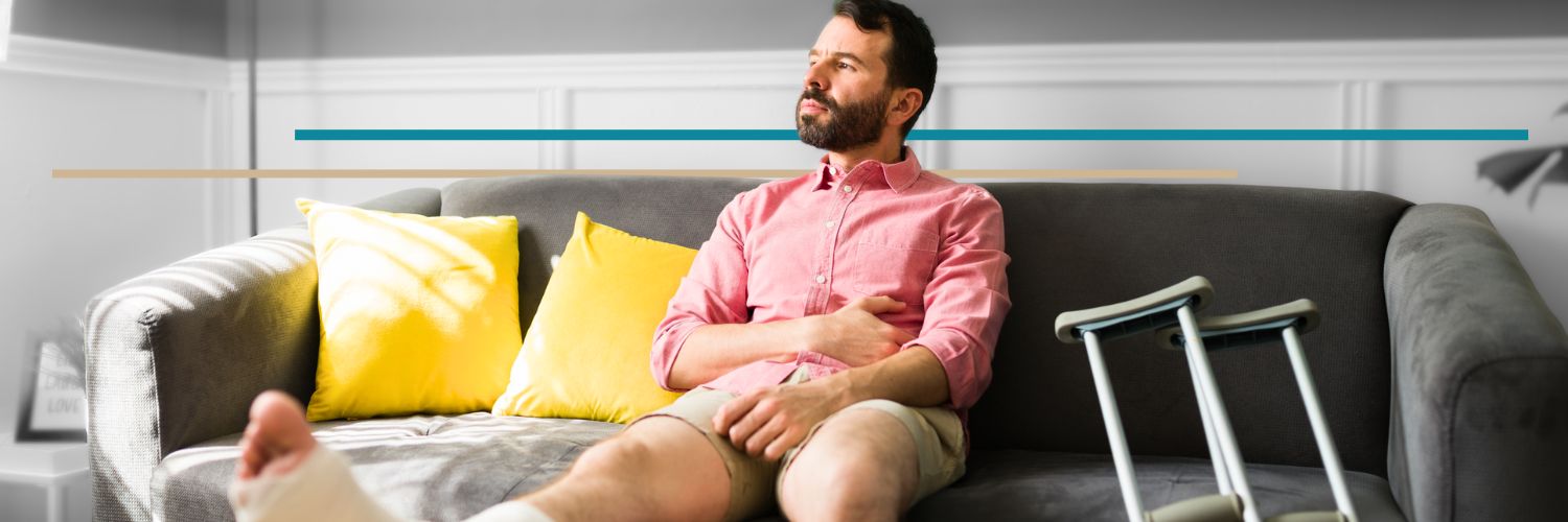 a man with a leg in a cast sitting on a couch looking out the window