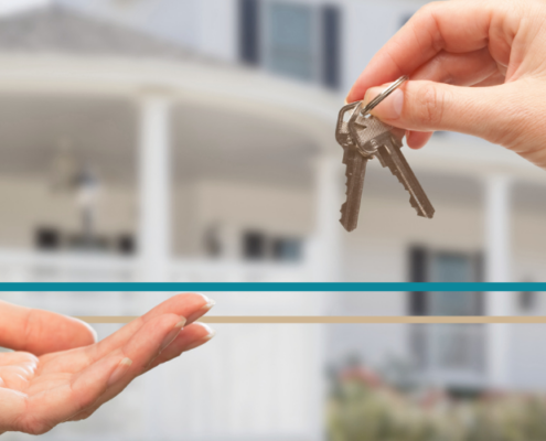 hands exchanging keys to a home in the background