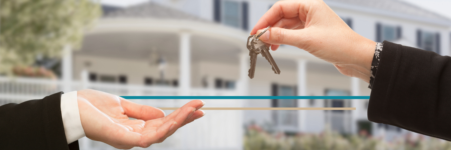 hands exchanging keys to a home in the background