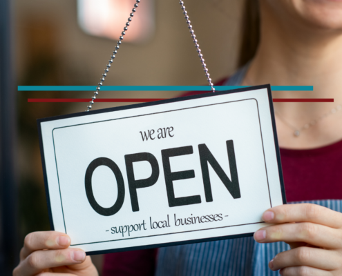 female business owner flipping a store open sign that says support local business