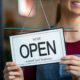 female business owner flipping a store open sign that says support local business
