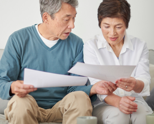 middle aged asian couple reviewing documents at home